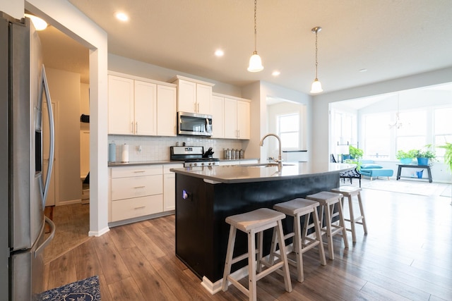 460 14th St NW, New Brighton, MN 55112 - kitchen with appliances with stainless steel finishes, a sink, wood finished floors, a breakfast bar, and tasteful backsplash