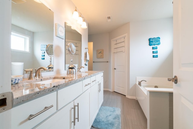 460 14th St NW, New Brighton, MN 55112 - bathroom with wood finished floors, a bath, double vanity, and baseboards