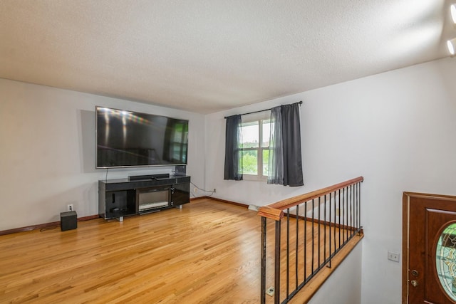 living room with wood finished floors, a textured ceiling, and baseboards