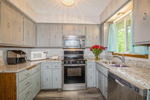 kitchen featuring appliances with stainless steel finishes, a sink, dark wood-style flooring, and gray cabinetry