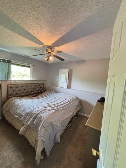 bedroom featuring dark carpet, a textured ceiling, a ceiling fan, and baseboards