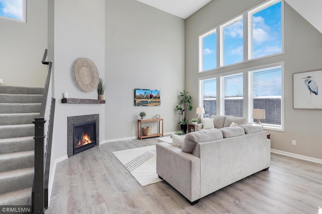 7122 156th St, Savage, MN 55378 - living room featuring a high ceiling, stairs, wood finished floors, baseboards, and a lit fireplace