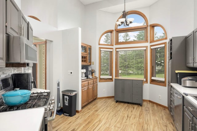 2222 Crosstown Blvd NE, Ham Lake, MN 55304 - kitchen with appliances with stainless steel finishes, gray cabinetry, a high ceiling, a chandelier, and light wood-type flooring