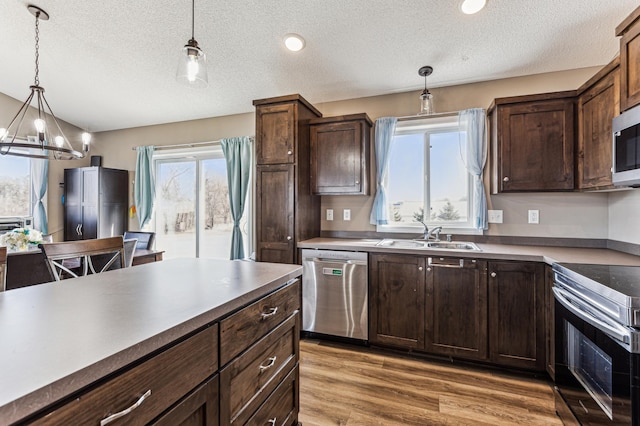 230 Newspaper Run NE, Kimball, MN 55353 - kitchen with stainless steel appliances, a sink, a textured ceiling, dark brown cabinetry, and hanging light fixtures