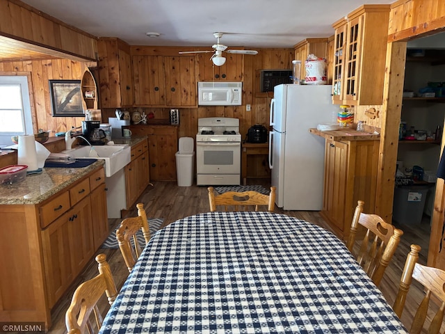 kitchen featuring white appliances, ceiling fan, wood walls, wood finished floors, and a sink