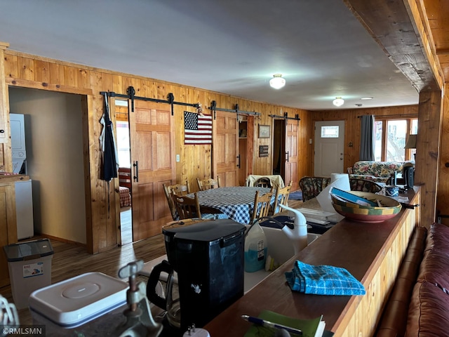 dining area with a barn door, wood walls, and wood finished floors