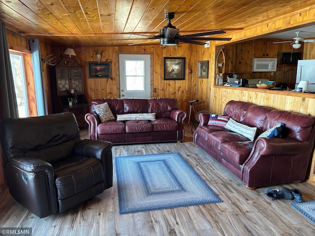 living room featuring ceiling fan, wood ceiling, wooden walls, and wood finished floors