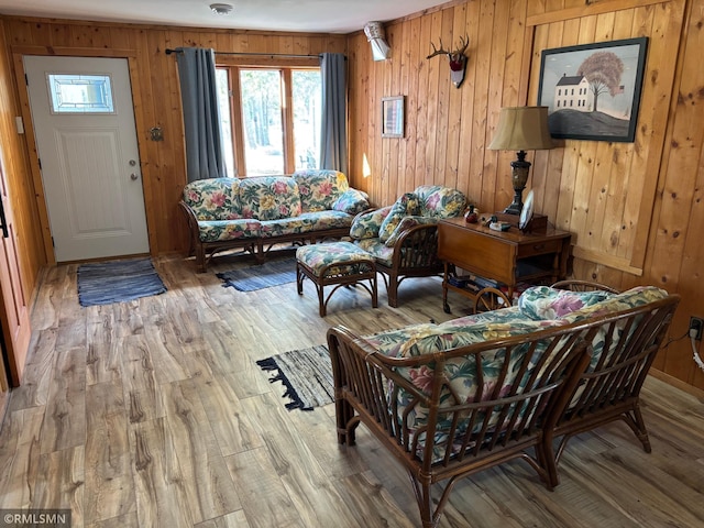 living area featuring wooden walls, light wood-type flooring, and baseboards