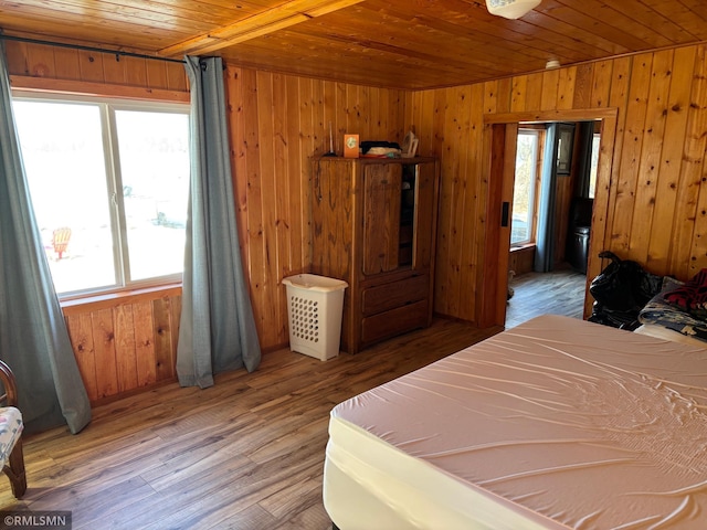 bedroom with wooden ceiling, multiple windows, wooden walls, and wood finished floors