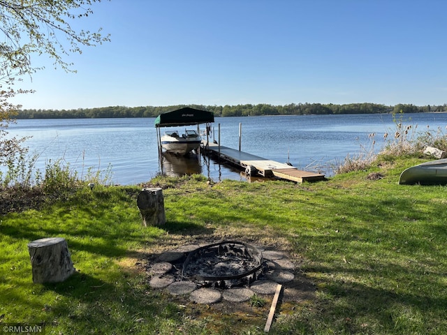 dock with an outdoor fire pit, a water view, and boat lift