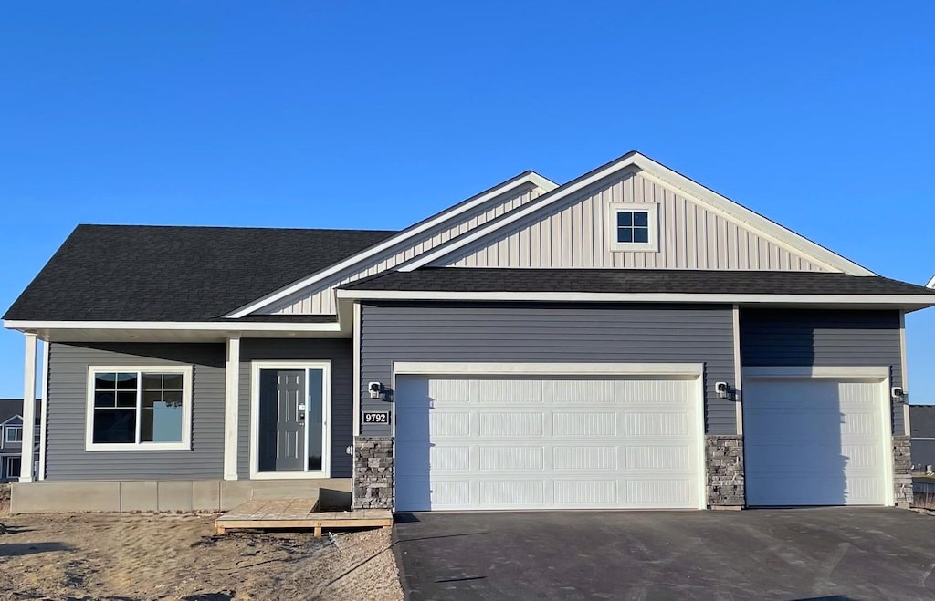 9792 32nd St NE, Saint Michael, MN 55376 - view of front facade with driveway, a shingled roof, a garage, and board and batten siding
