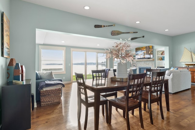 dining space featuring wood finished floors, baseboards, a glass covered fireplace, and recessed lighting