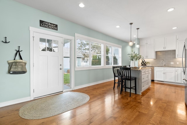 kitchen with baseboards, a center island, white cabinets, decorative backsplash, and wood finished floors