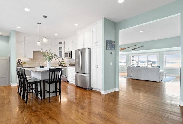 kitchen with decorative backsplash, white cabinetry, a kitchen bar, and stainless steel appliances