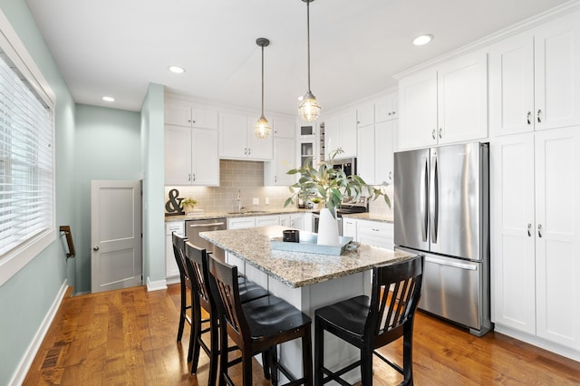 kitchen with dark wood-type flooring, freestanding refrigerator, a sink, and a breakfast bar