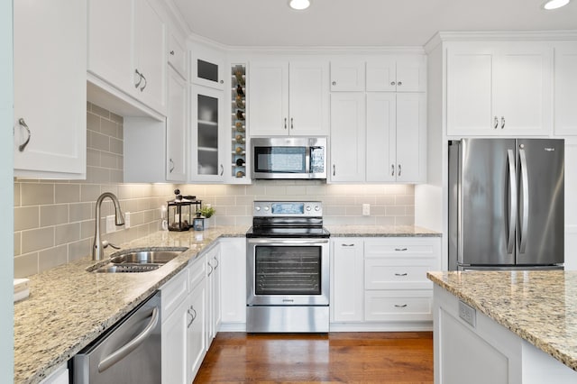 kitchen with tasteful backsplash, white cabinets, a sink, appliances with stainless steel finishes, and dark wood finished floors