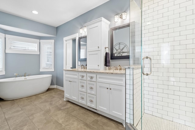 bathroom featuring a freestanding tub, baseboards, double vanity, a shower stall, and a sink