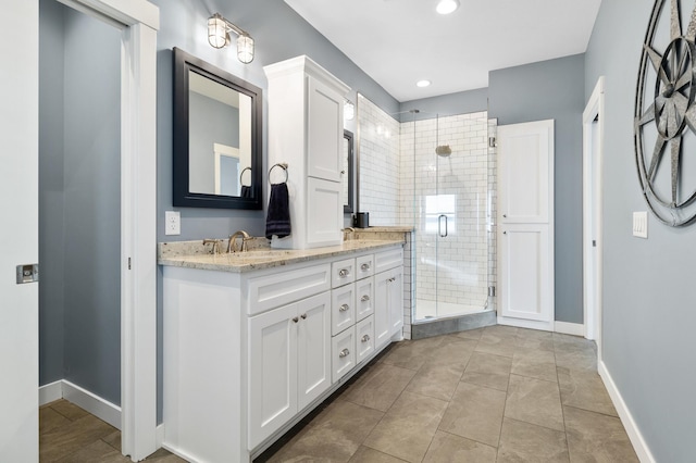bathroom featuring a shower stall, a sink, baseboards, and double vanity