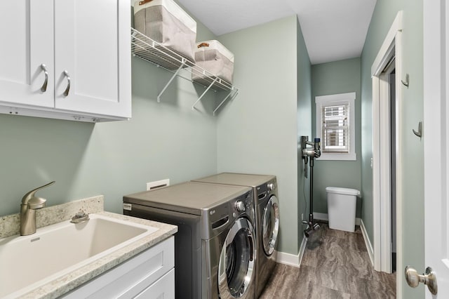 washroom featuring independent washer and dryer, baseboards, a sink, and cabinet space