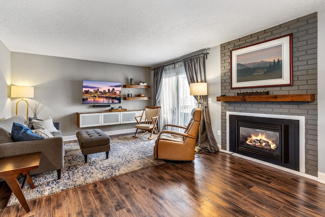 living room featuring a textured ceiling, a brick fireplace, and wood finished floors