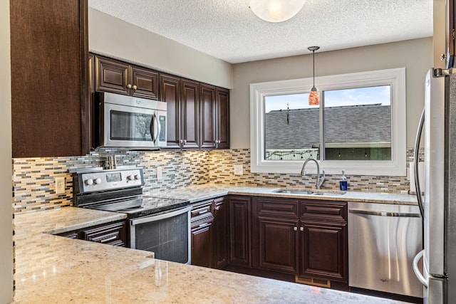 kitchen featuring dark brown cabinets, appliances with stainless steel finishes, a sink, a textured ceiling, and backsplash