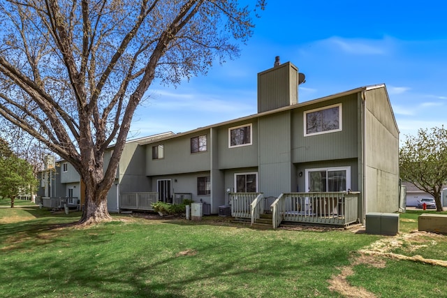 back of house featuring central AC unit, a wooden deck, a yard, and a chimney