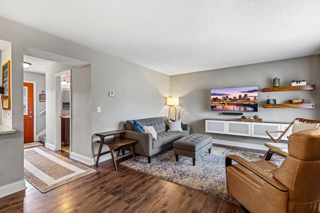 living area with baseboards, a textured ceiling, and wood finished floors