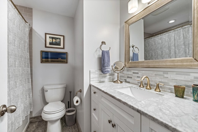 full bath featuring vanity, tasteful backsplash, baseboards, and toilet