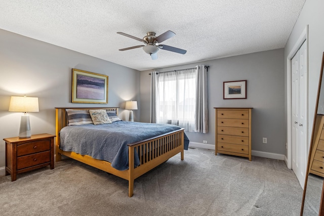 bedroom featuring ceiling fan, a textured ceiling, baseboards, a closet, and carpet flooring