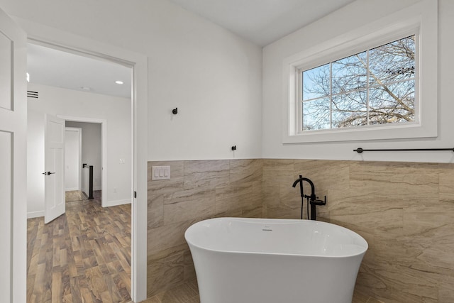 2308 Shadywood Rd, Orono, MN 55391 - bathroom with tile walls, a freestanding bath, wood finished floors, and wainscoting