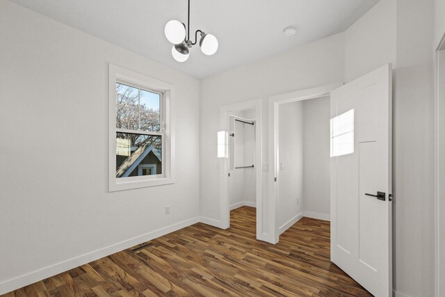 2308 Shadywood Rd, Orono, MN 55391 - unfurnished bedroom with baseboards, a chandelier, dark wood finished floors, a walk in closet, and a closet