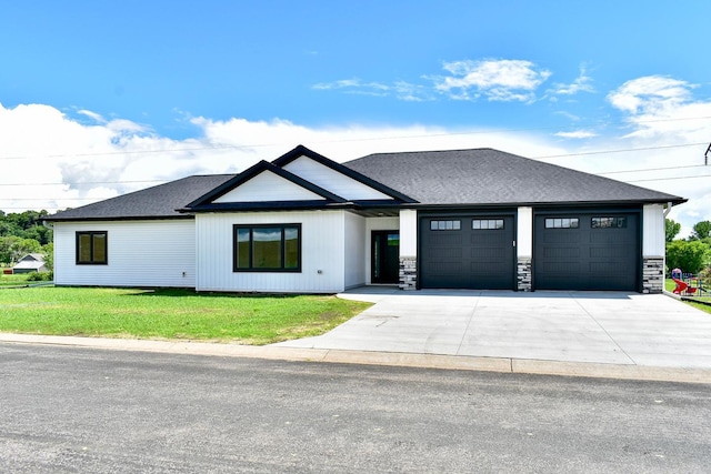 view of front of property with a front yard, an attached garage, driveway, and a shingled roof