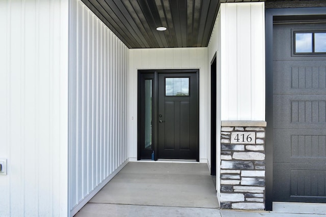 view of exterior entry with board and batten siding and stone siding