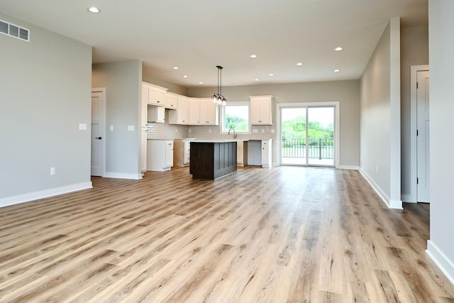 unfurnished living room featuring a sink, visible vents, recessed lighting, and light wood finished floors