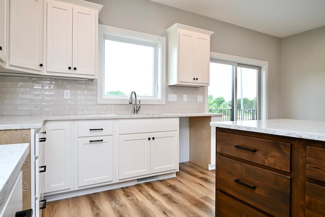 kitchen featuring light wood finished floors, white cabinetry, and a sink