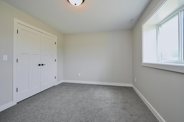 unfurnished bedroom featuring baseboards, carpet floors, and a closet