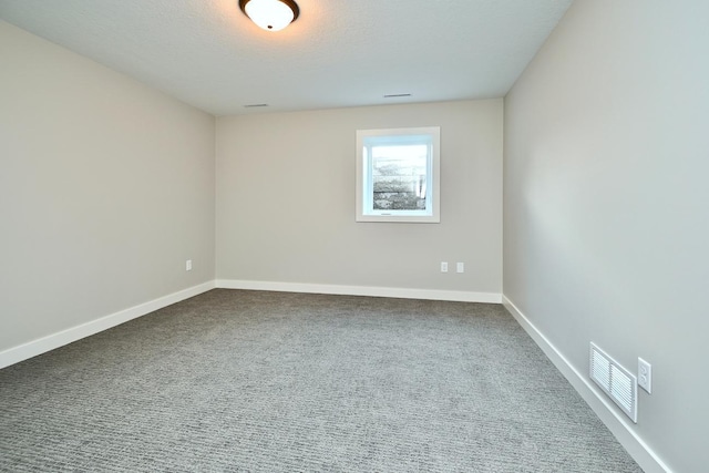 unfurnished room featuring visible vents, dark carpet, a textured ceiling, and baseboards