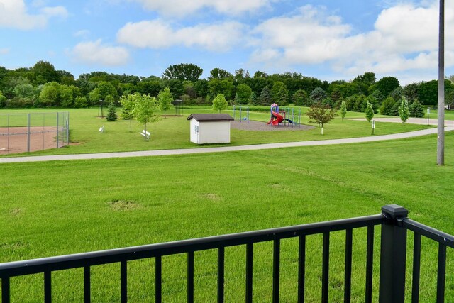 surrounding community with a lawn, an outdoor structure, a storage shed, and a playground