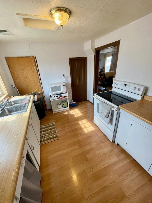 320 8th St SE, Staples, MN 56479 - kitchen featuring white electric stove, light wood-style floors, and white cabinetry