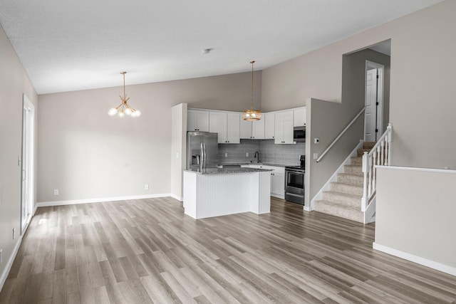 kitchen with a sink, lofted ceiling, a chandelier, white cabinets, and appliances with stainless steel finishes