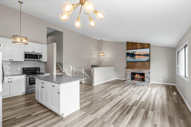 kitchen with a chandelier, stainless steel appliances, light wood finished floors, and tasteful backsplash