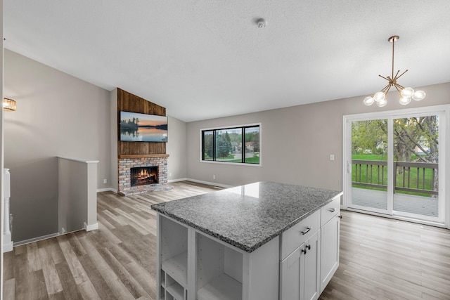 kitchen with vaulted ceiling, light wood-style flooring, a kitchen island, and light stone countertops