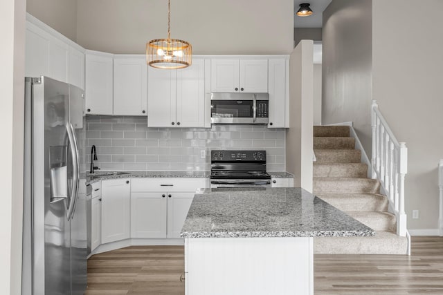 kitchen with a sink, light wood finished floors, white cabinetry, and appliances with stainless steel finishes