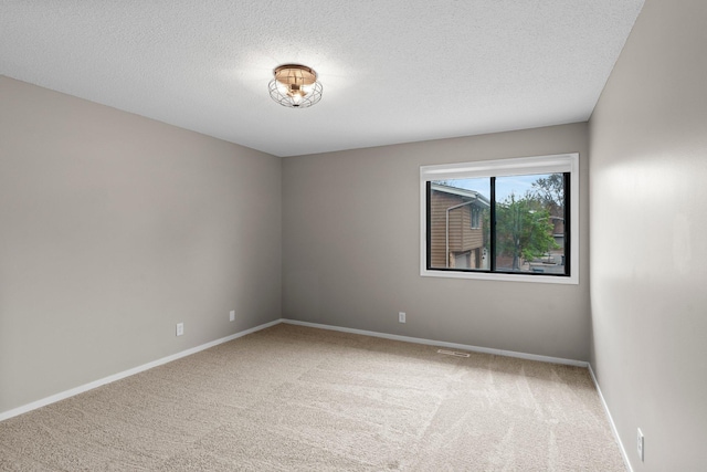 unfurnished room featuring baseboards, a textured ceiling, visible vents, and carpet