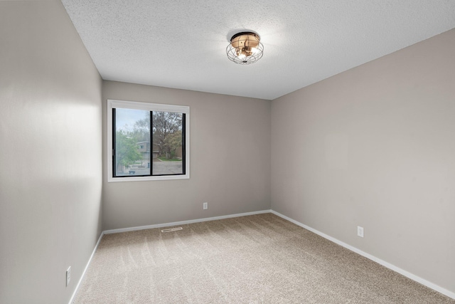 spare room with a textured ceiling, carpet floors, baseboards, and visible vents