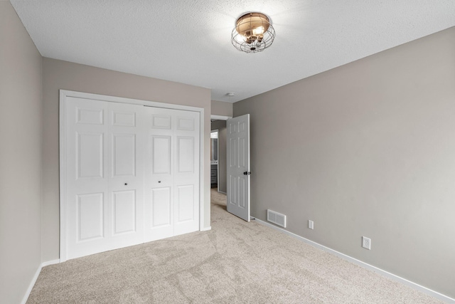 unfurnished bedroom featuring carpet, visible vents, baseboards, and a closet