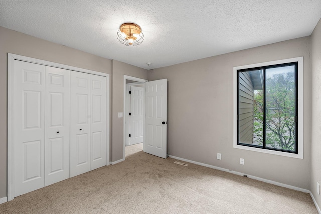 unfurnished bedroom with a textured ceiling, carpet floors, baseboards, and a closet