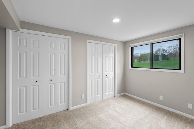 unfurnished bedroom with baseboards, recessed lighting, two closets, and carpet floors