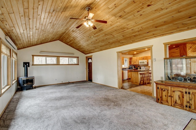 unfurnished living room featuring a wood stove, ceiling fan, light carpet, and wooden ceiling
