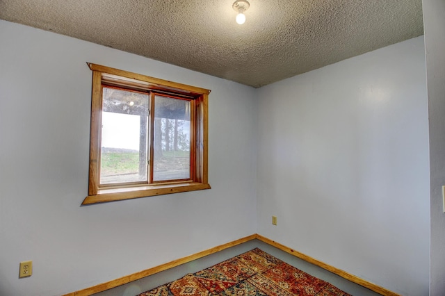 unfurnished room with baseboards and a textured ceiling